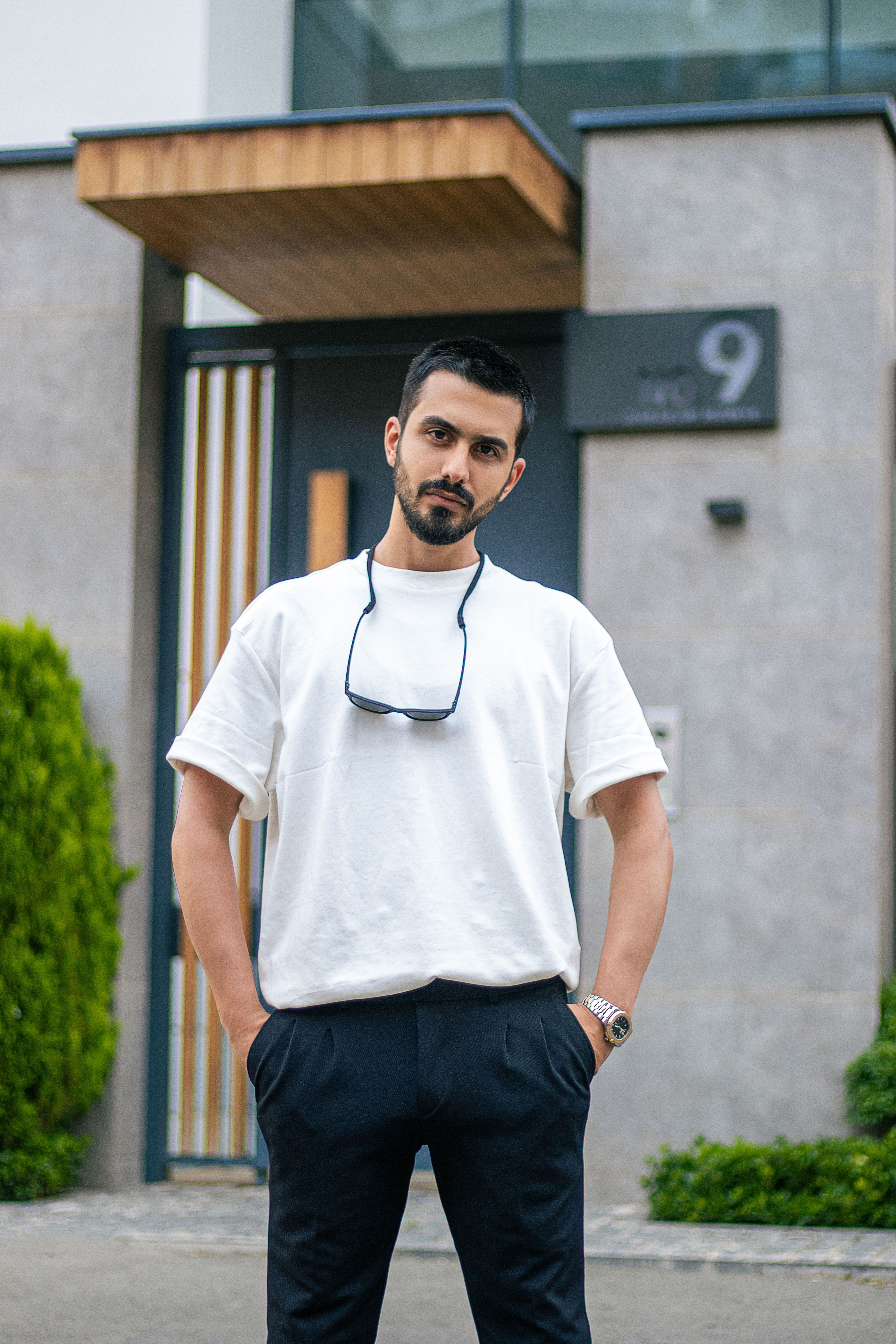 Casual portrait of a man standing confidently in front of a modern urban building.