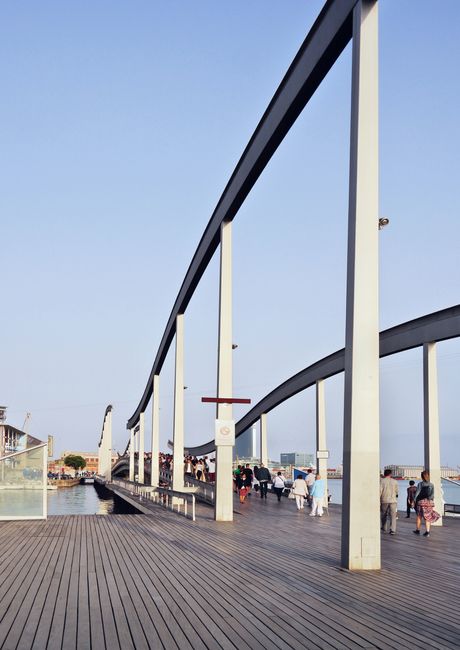 Contemporary boardwalk and abstract architecture in Port Vell, Barcelona with blue sky.