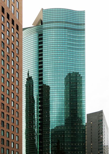 Contemporary glass skyscraper reflecting urban Tokyo cityscape, showcasing modern architecture.