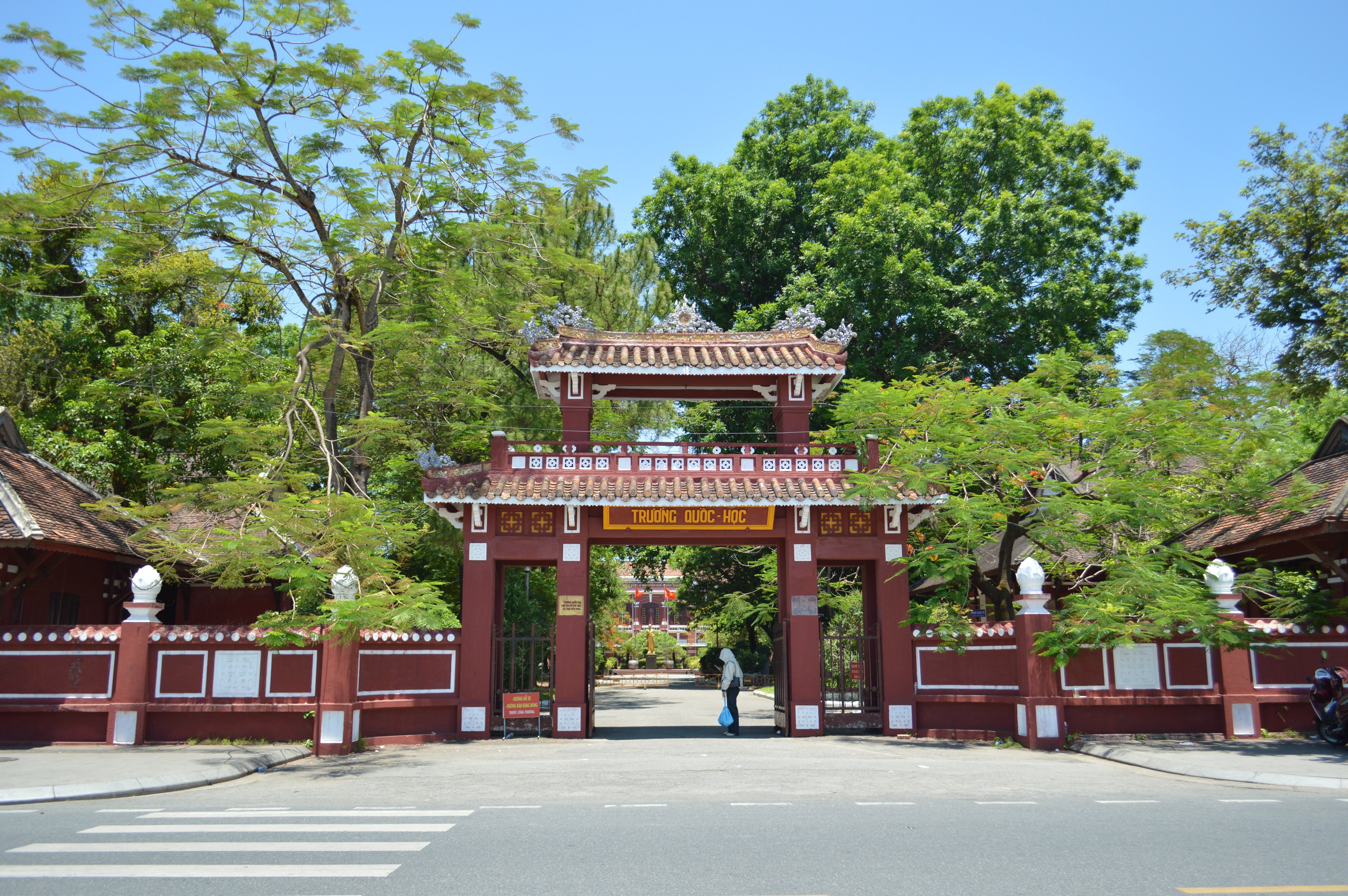 Traditional Vietnamese gateway of a historic school in a lush setting.