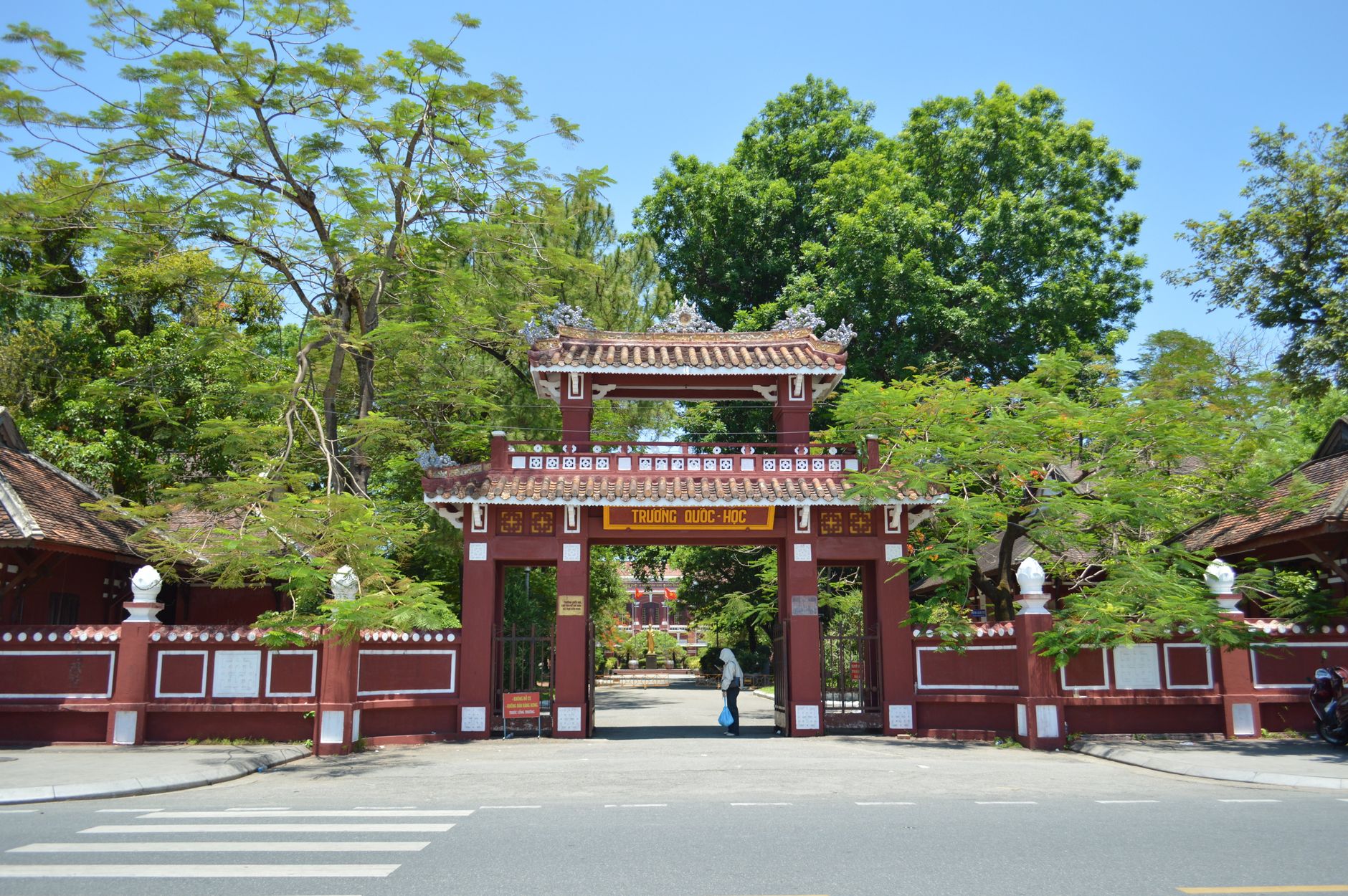 Nhà nhân học ghi chép bên ngoài một sân đấu Bali, dân làng trò chuyện dưới bóng cây nhiệt đới