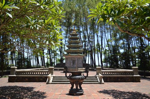 Free An ornate Buddhist pagoda surrounded by lush greenery and trees on a sunny day. Stock Photo