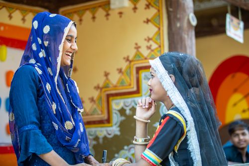 Free Colorful portrayal of women in traditional Rajasthani clothing interacting outdoors. Stock Photo