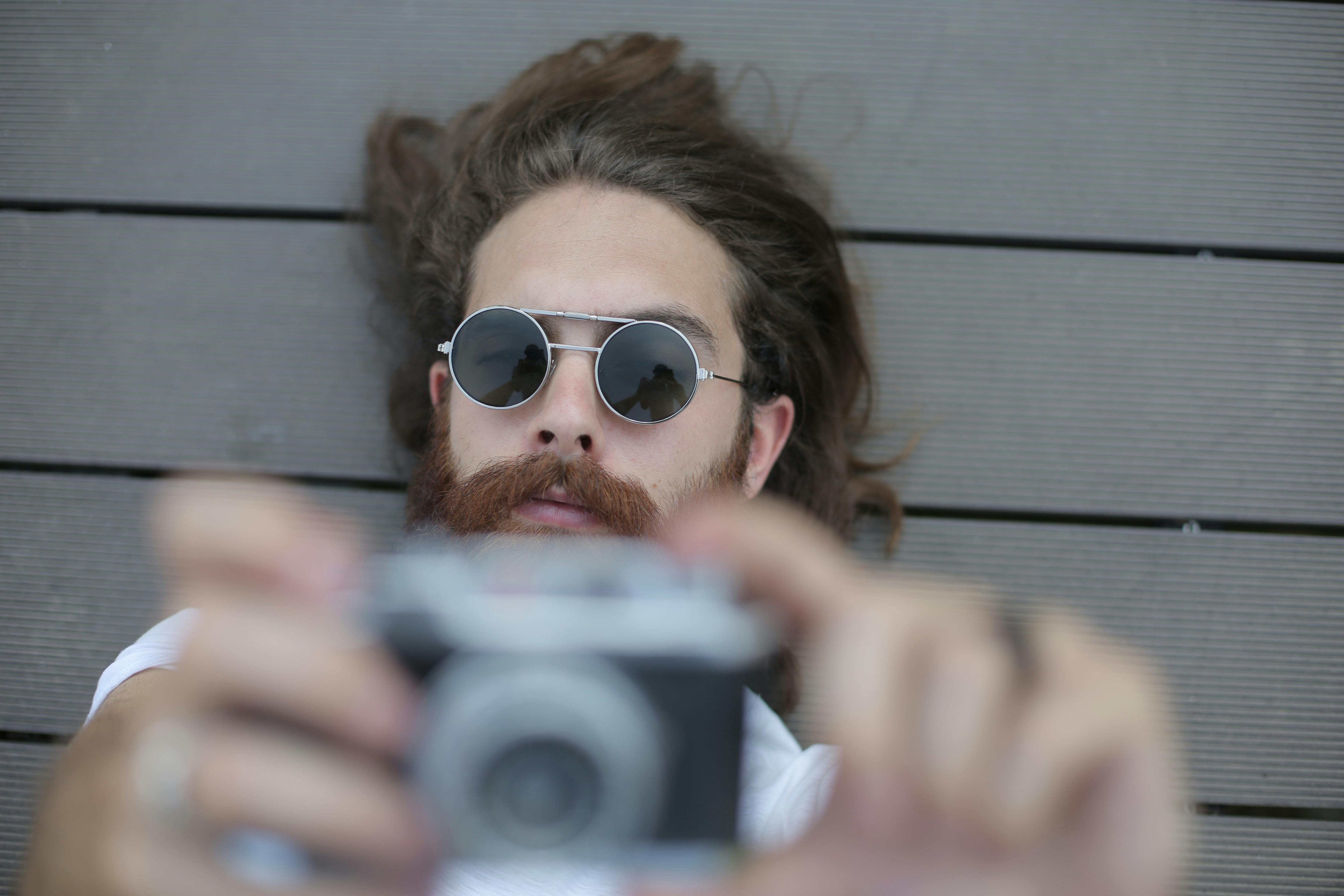 Man in Silver Framed Sunglasses Holding Black and Gray Camera · Free ...