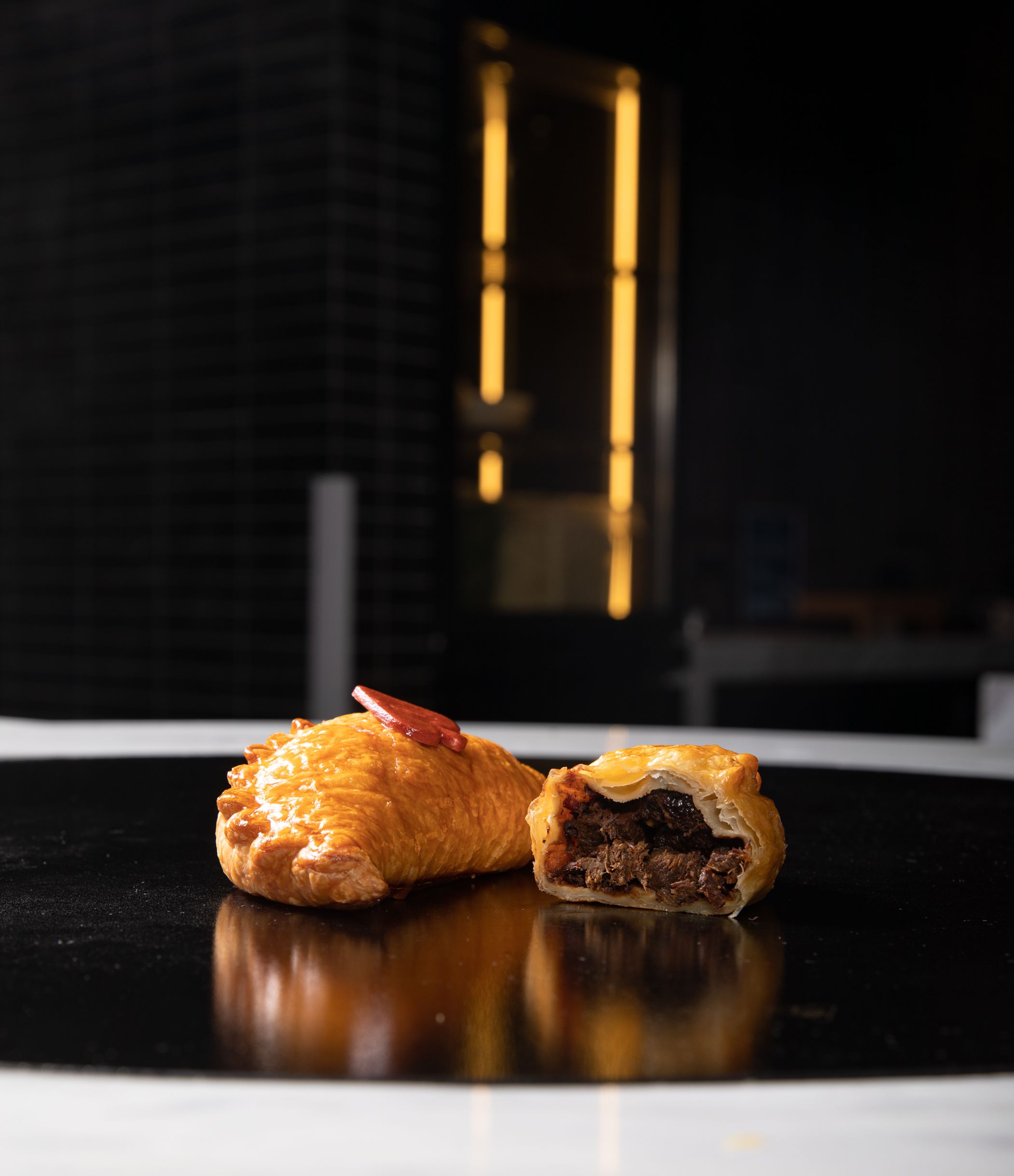 Gratuit Pâtisserie salée à la viande coupée en deux sur une surface noire brillante. Photos