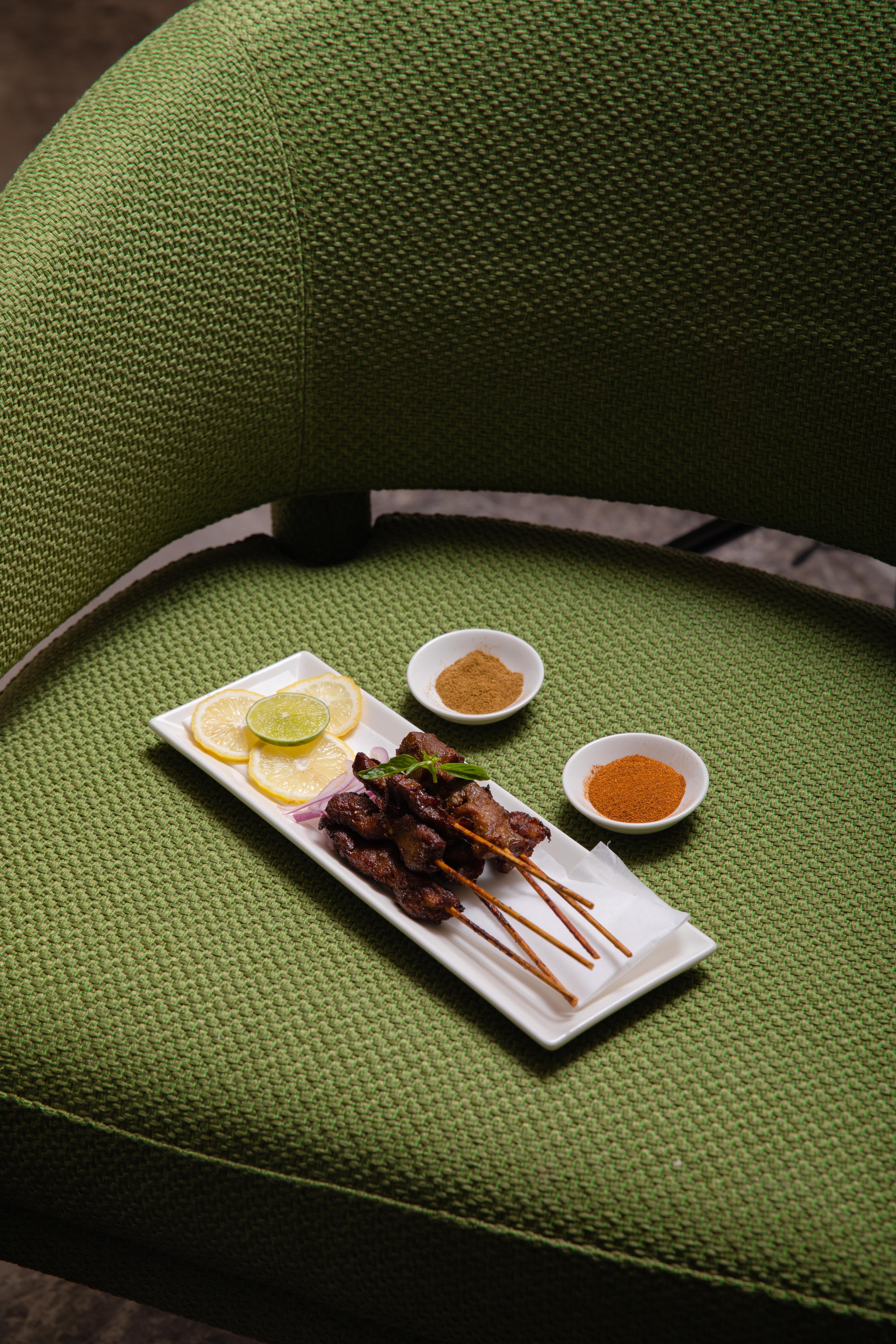 Grilled Peruvian anticuchos skewers with charred beef heart and bright green aji verde sauce on the side