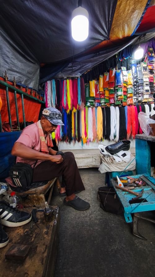 Free Cobbler working amidst colorful laces in a small repair shop. Stock Photo