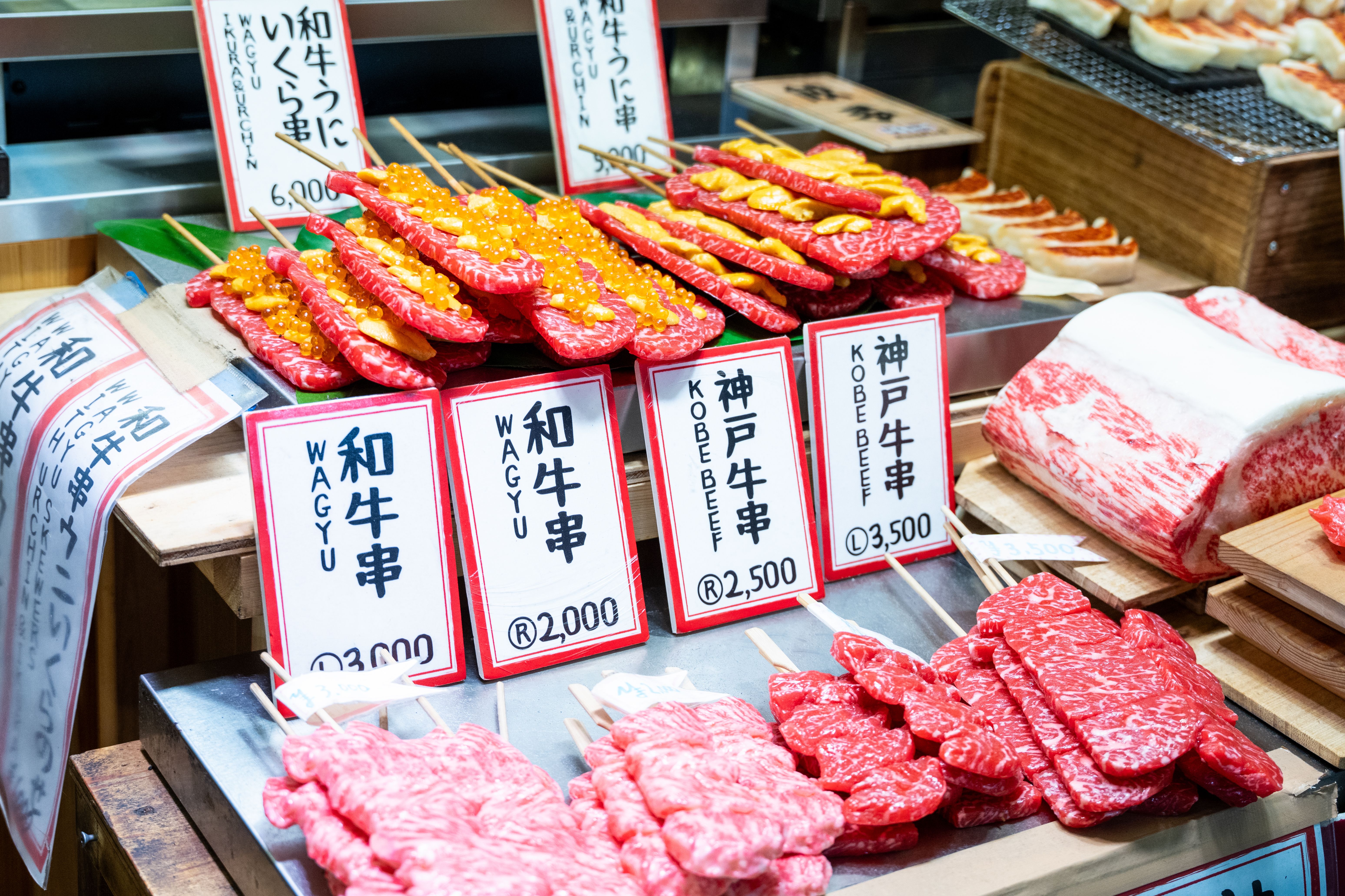Colorful display of Wagyu and Kobe beef skewers at a Japanese market, showcasing premium cuts.