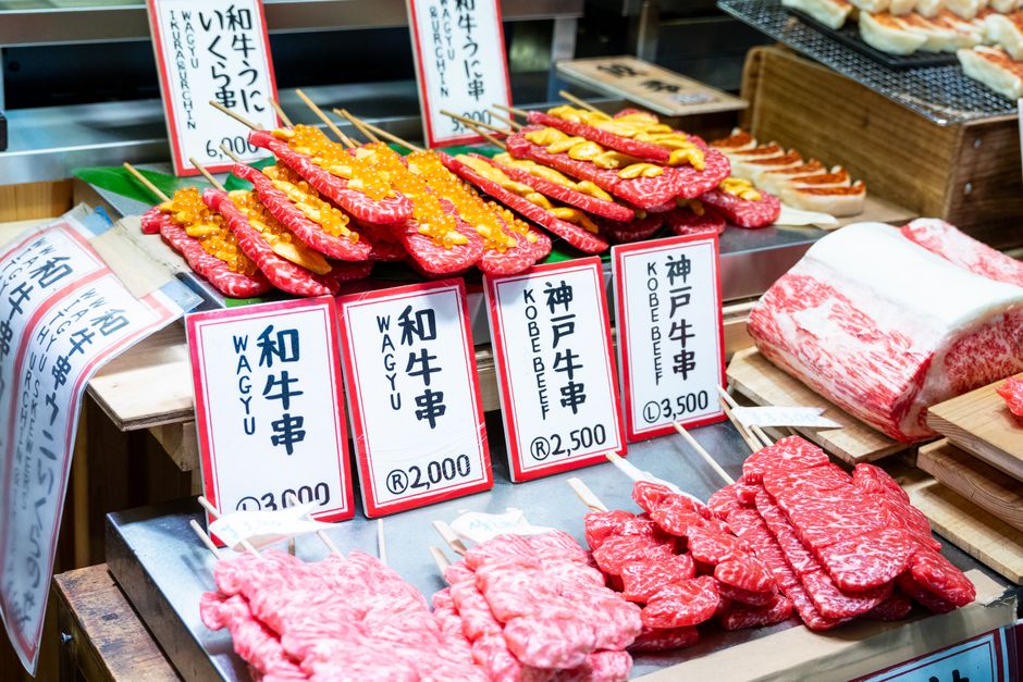 Colorful display of Wagyu and Kobe beef skewers at a Japanese market, showcasing premium cuts.