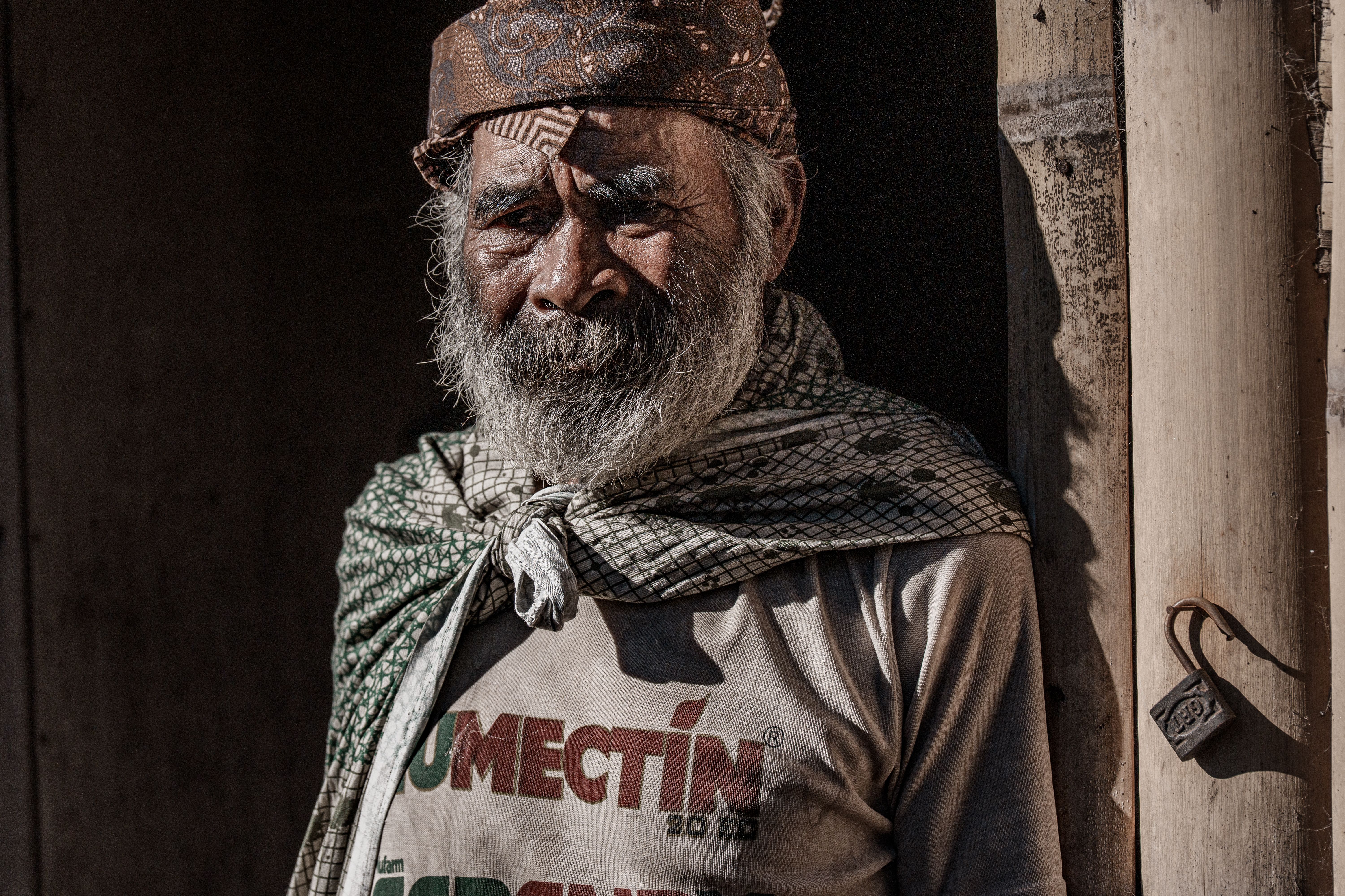 Close-up portrait of a senior man wearing traditional attire in East Java, Indonesia. Sunlit and evocative expression.