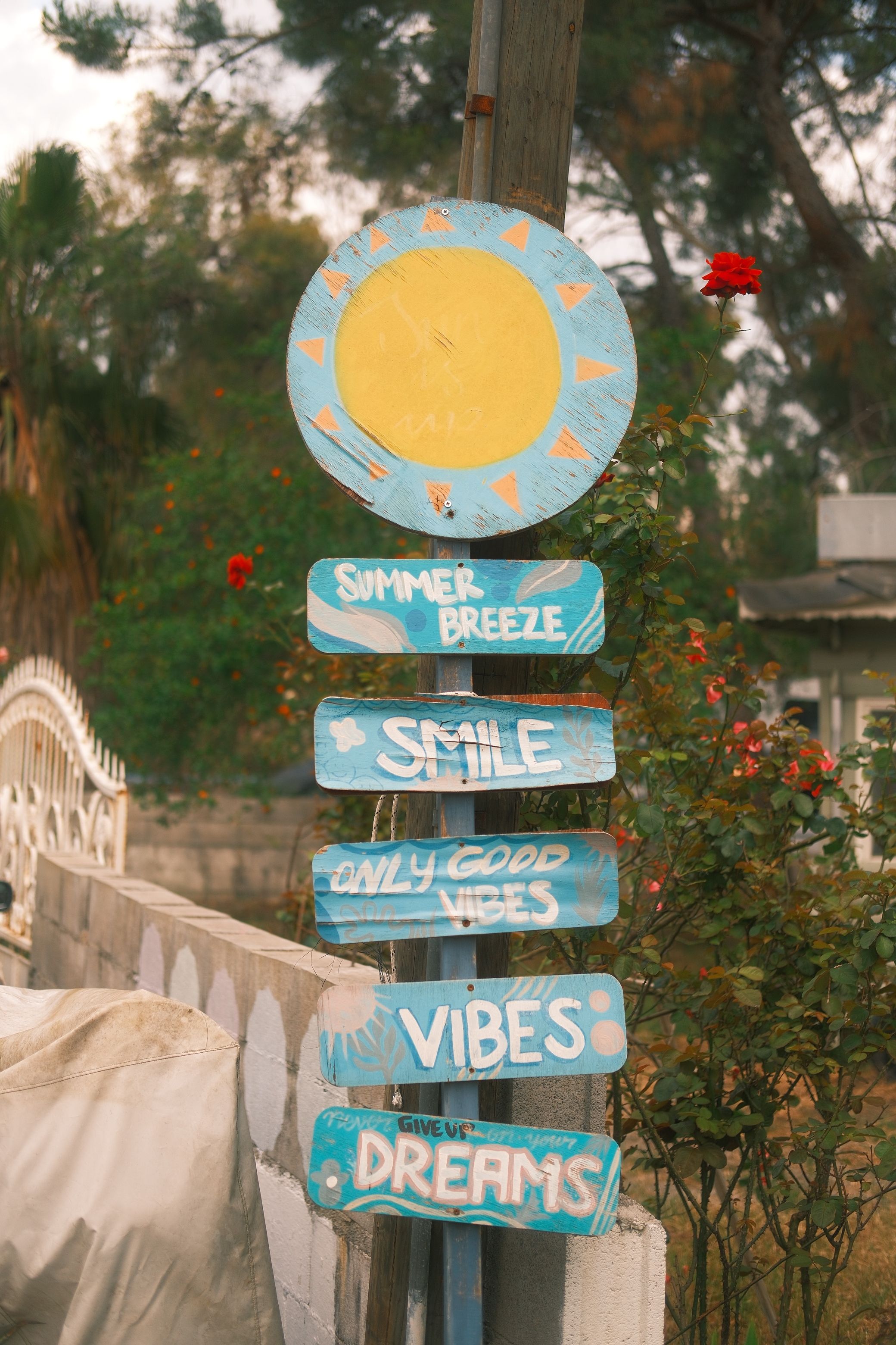 Vibrant wooden sign with positive messages in a lush garden backdrop.