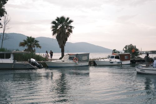Free Tranquil boats moored at a lakeside marina during a serene sunset with palm trees. Stock Photo