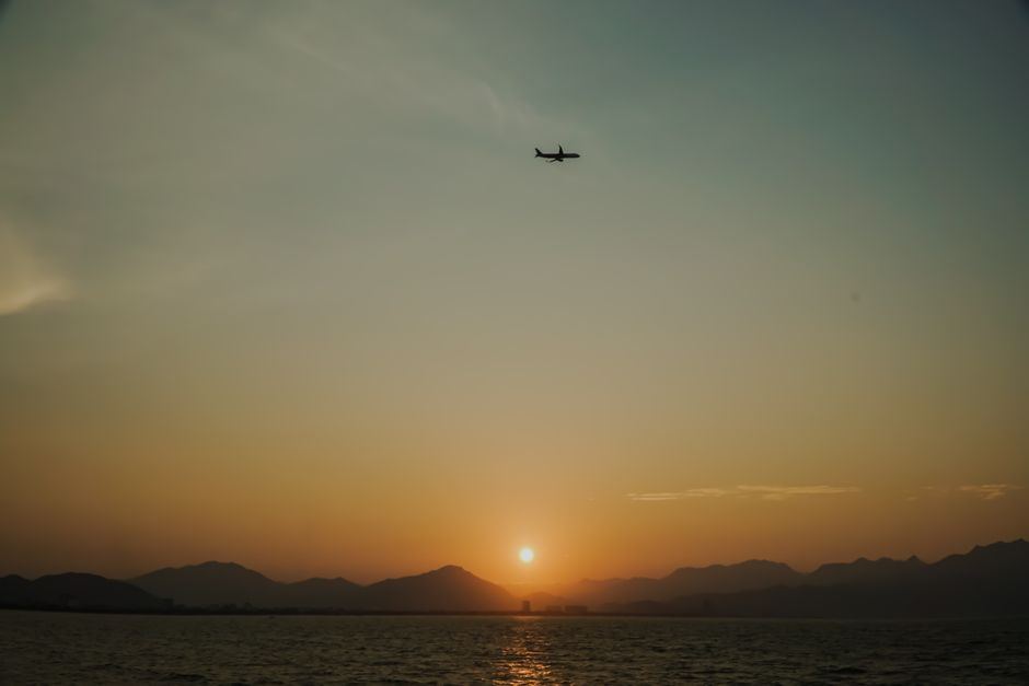 Silhouette of an airplane flying over the ocean at sunset in Da Nang, Vietnam.