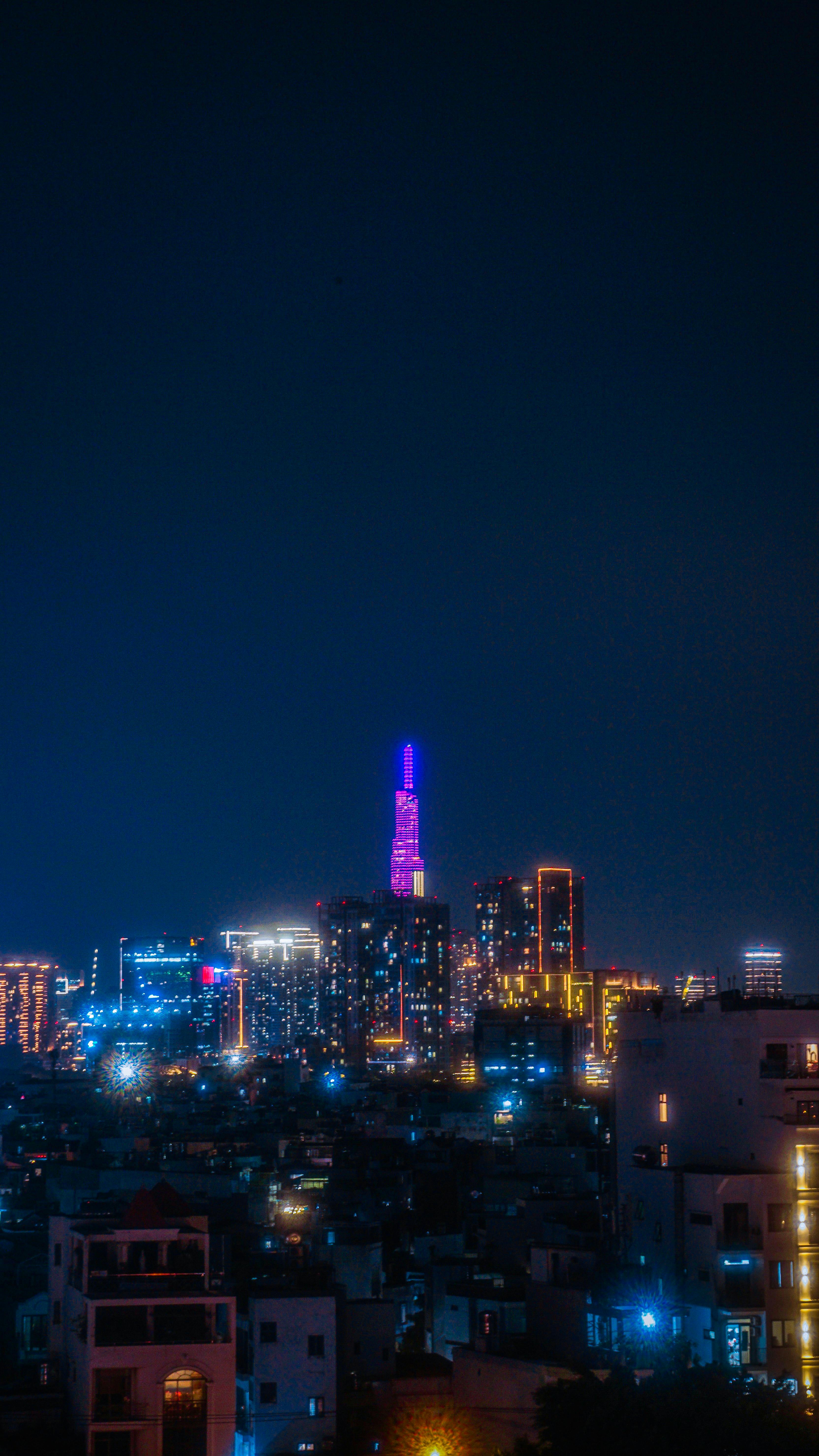 Colorful cityscape of Ho Chi Minh City with illuminated skyscrapers at night.