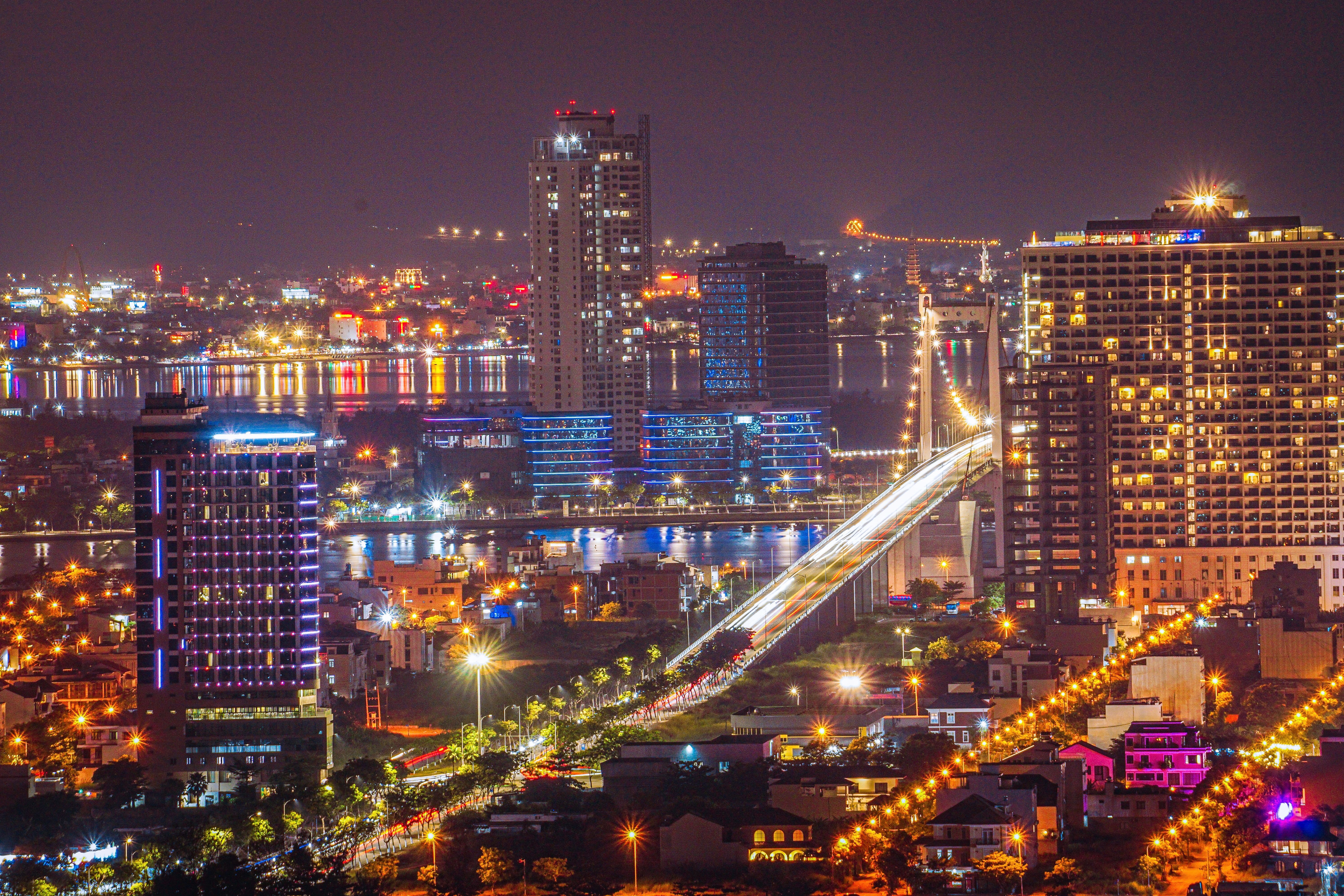 Vibrant night view of Da Nang, Vietnam, showcasing an illuminated bridge and city skyline.