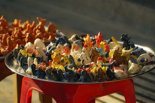 A collection of vibrant ceramic animal figurines displayed on a tray in Da Nang, Vietnam.