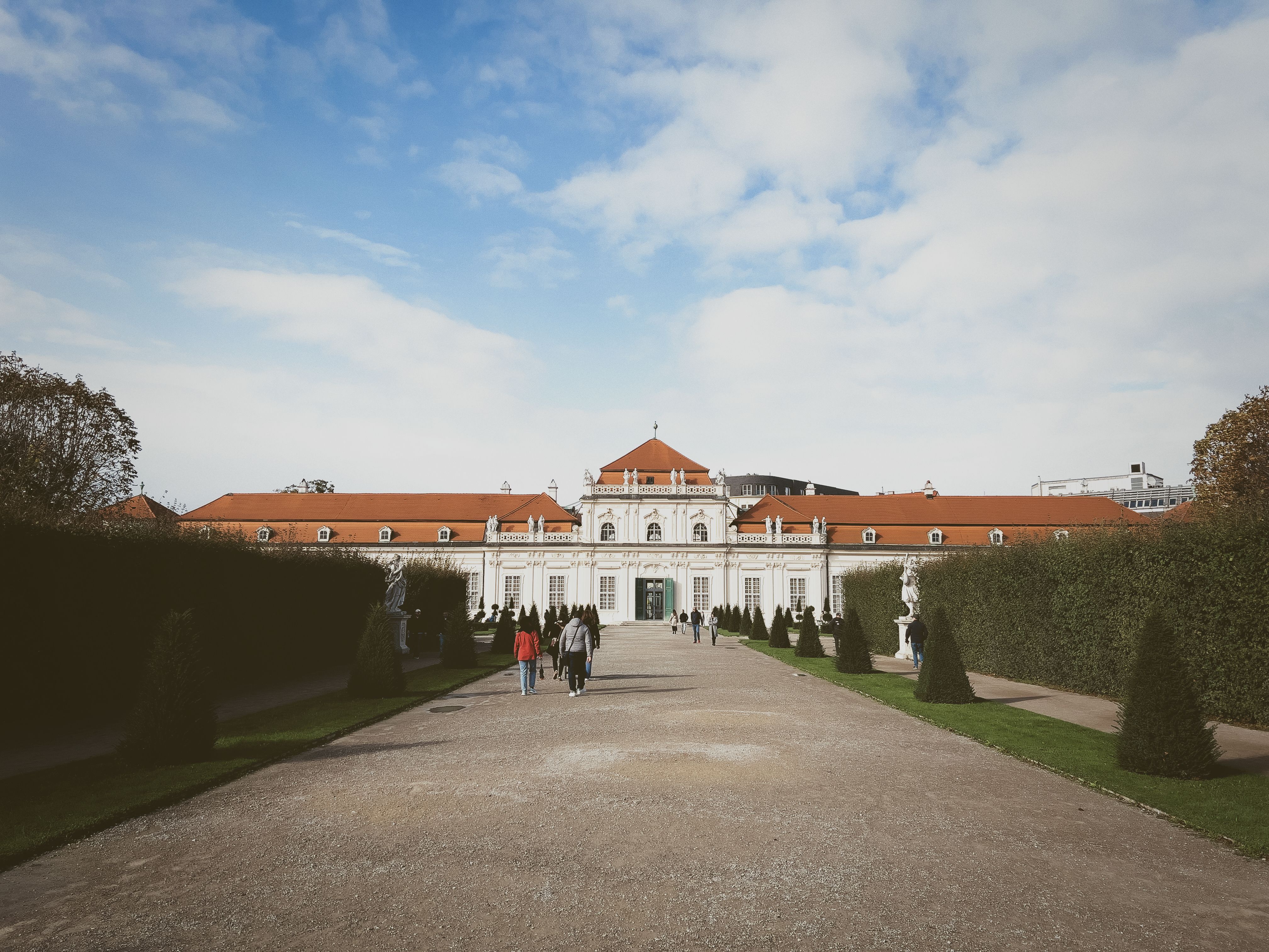 Free A picturesque Baroque palace with red roofs and lush gardens under a blue sky. Stock Photo