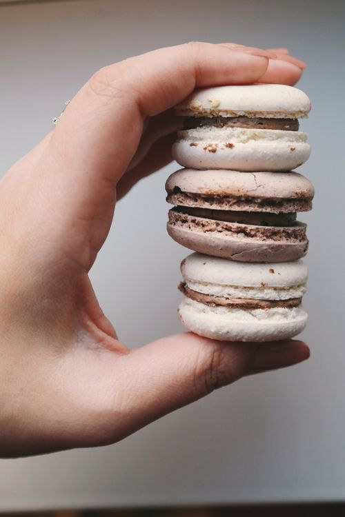 Free Delicious stack of macarons held by a hand. Perfect for dessert and food photography themes. Stock Photo