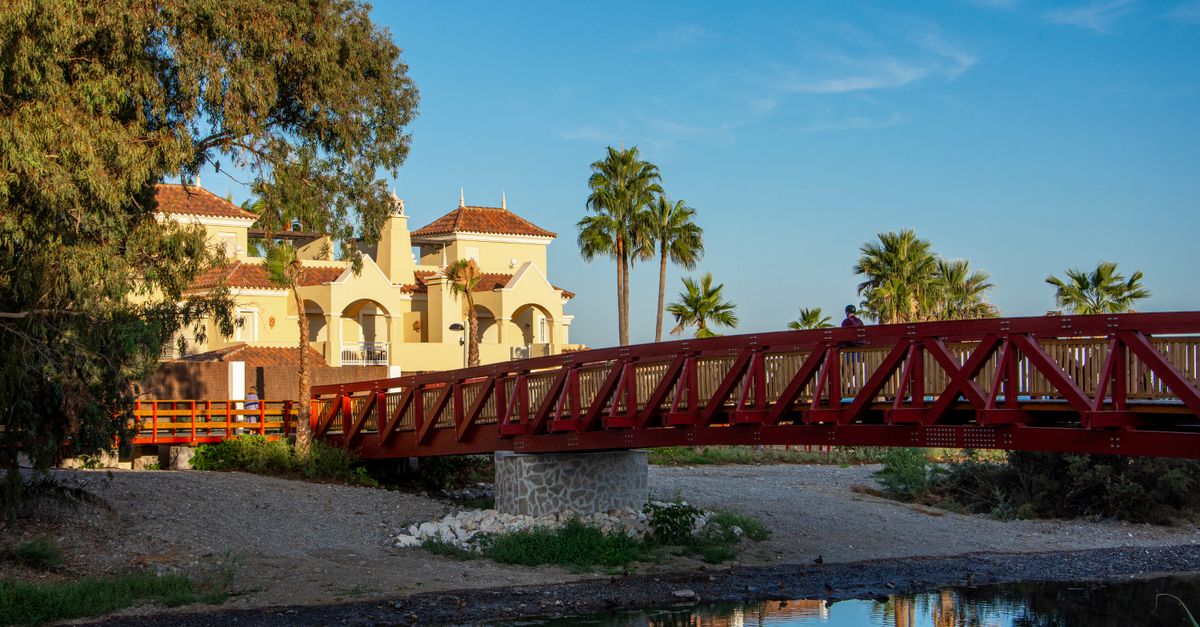 Scenic view of a Spanish villa next to a red bridge in Marbella, AndalucĂa, Spain, on a sunny day.