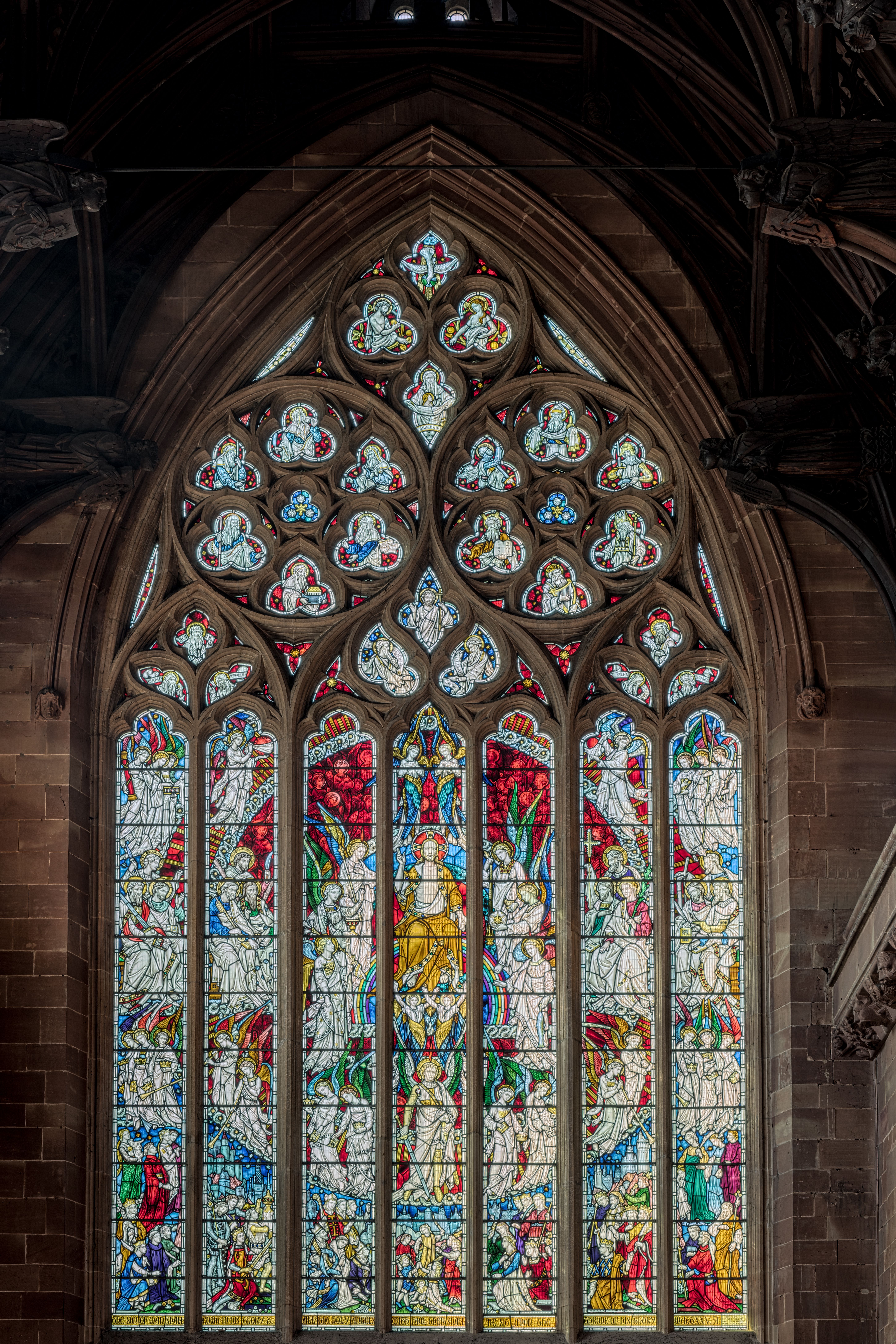 Detailed stained glass window depicting religious scenes in a gothic church setting.