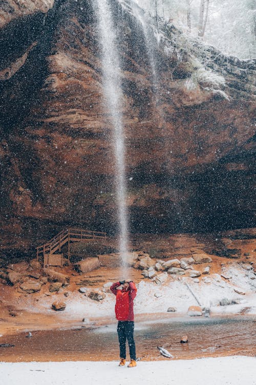 Person in Red Jacket Standing Near Waterfalls