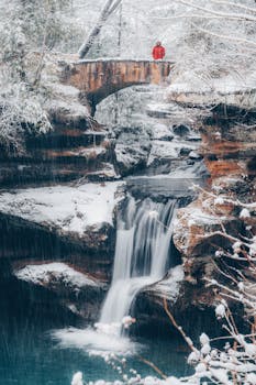 冬季仙境中，一座桥横跨在白雪皑皑森林的冰冻瀑布上