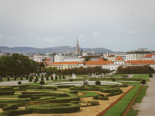 Free A scenic view of Vienna's Belvedere Gardens and city skyline with mountains in the background. Stock Photo