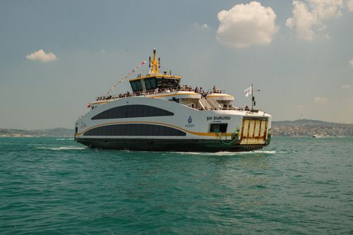 Free Ferry crossing the Bosphorus in Istanbul with city skyline in background, under a clear blue sky. Stock Photo
