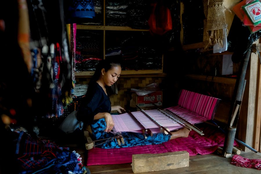 Perajin menenun kain tradisional dalam suasana bengkel yang hangat
