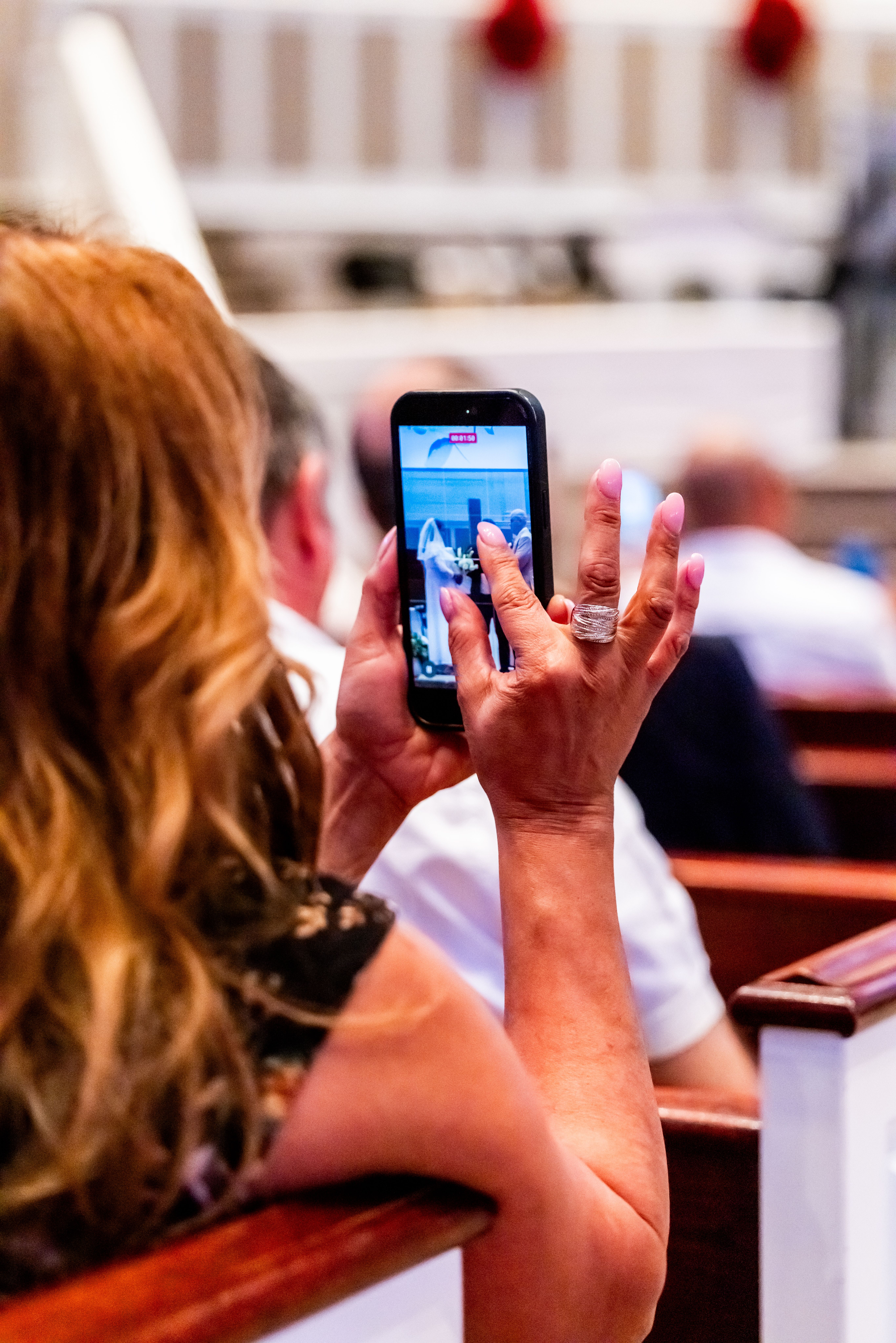 A woman taking a photo with her smartphone during a church event, showcasing modern technology in traditional settings.