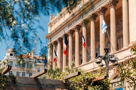 View of the historic Bourse et Chambre de Commerce building in Marseille with French flags.