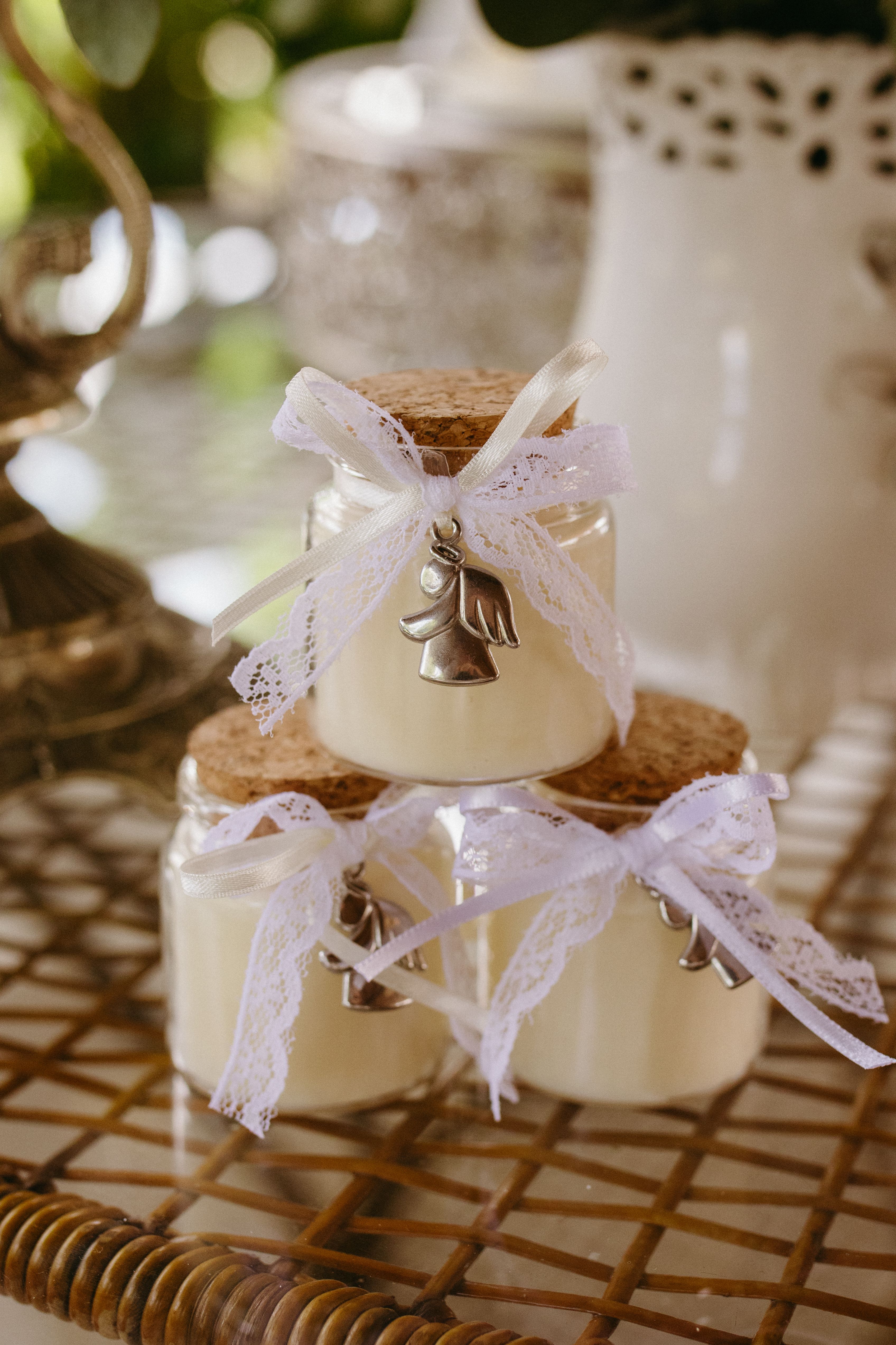Elegant mason jars with lace and angel decorations on a wicker surface, perfect for weddings or rustic events.