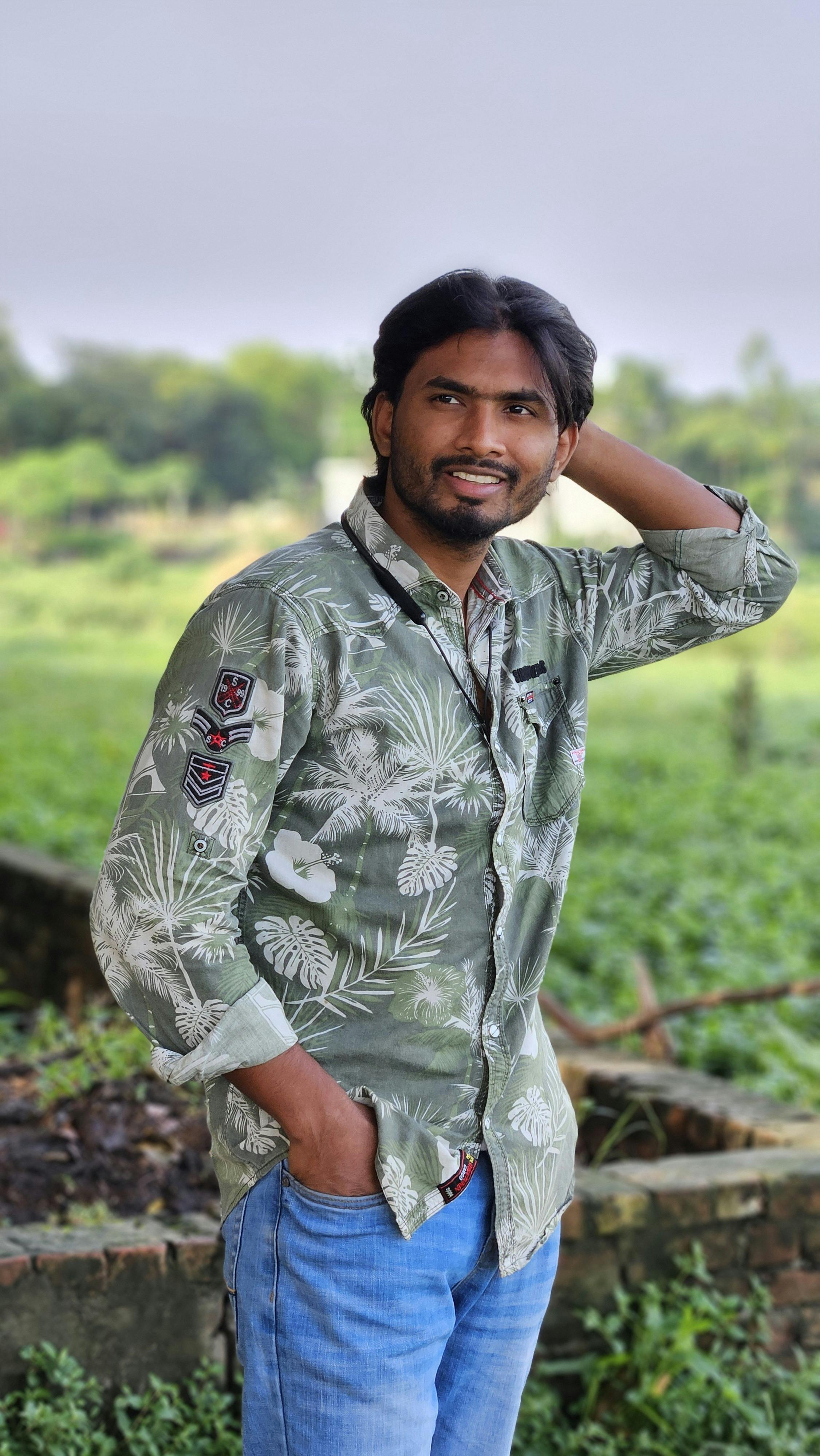 Portrait of a smiling man outdoors with lush greenery in the background.