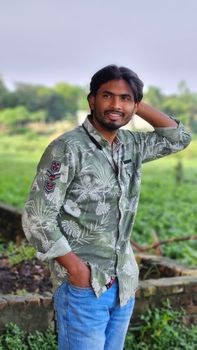 Portrait of a smiling man outdoors with lush greenery in the background.