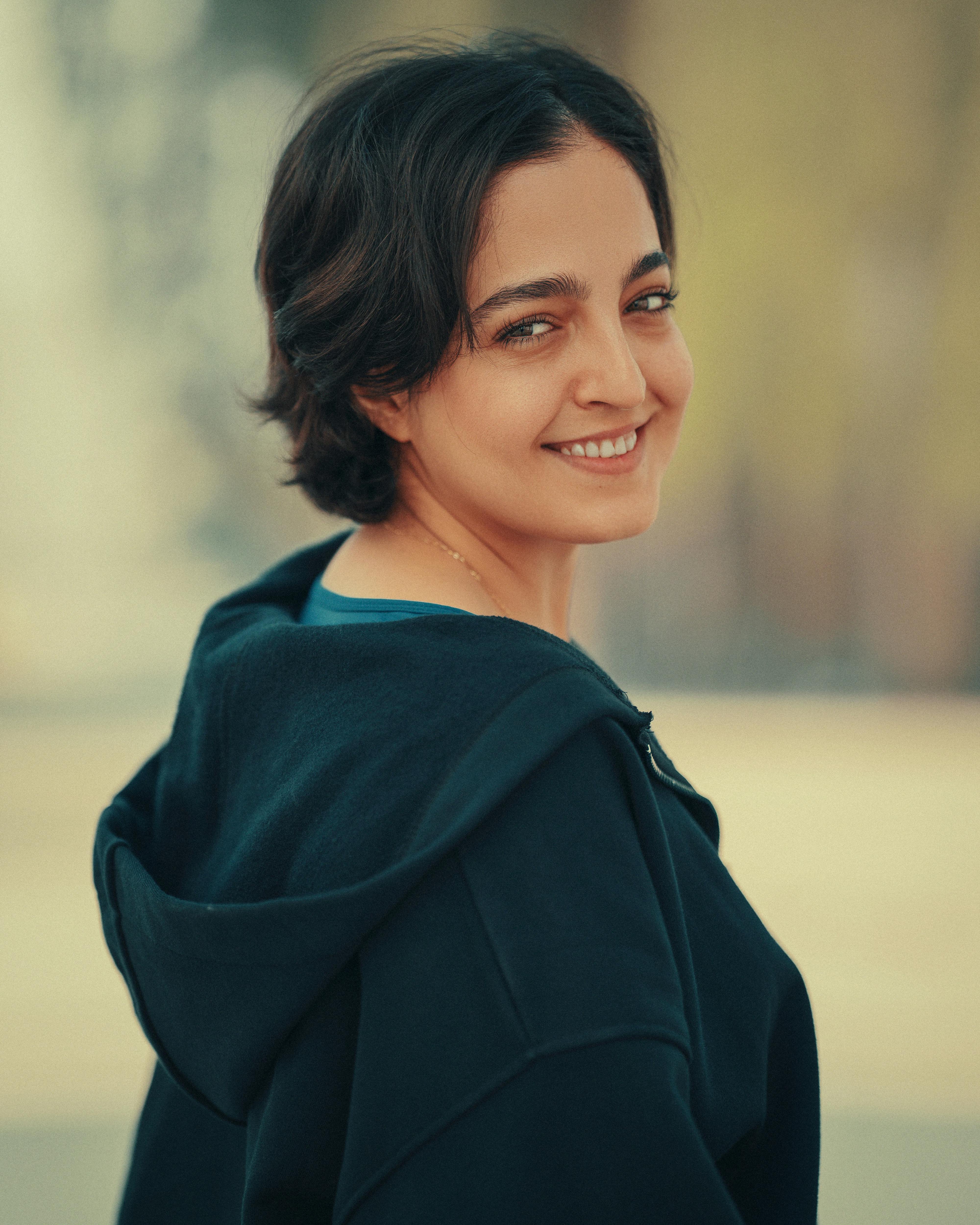 Portrait of a young woman smiling outdoors in casual fashion.