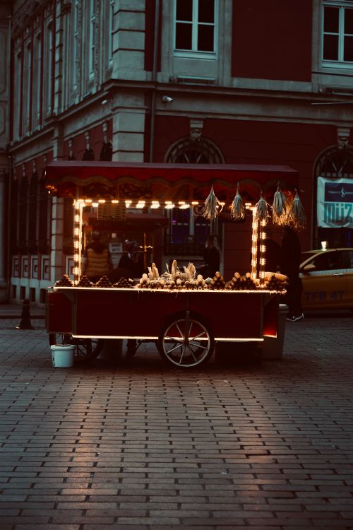 Free A charming street food cart brightly lit on a cobblestone street during twilight. Stock Photo