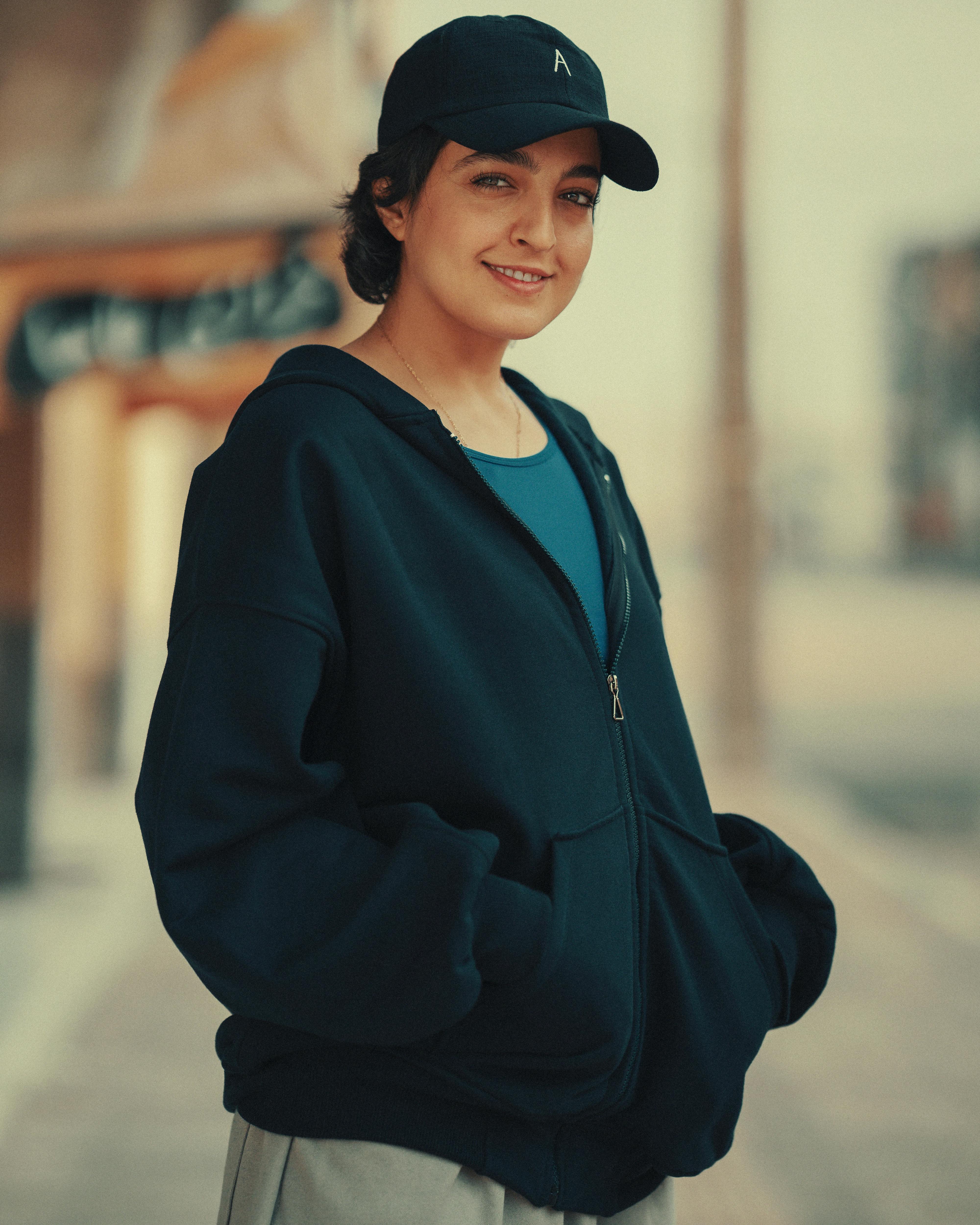 A candid street portrait of a smiling woman in casual attire during golden hour.