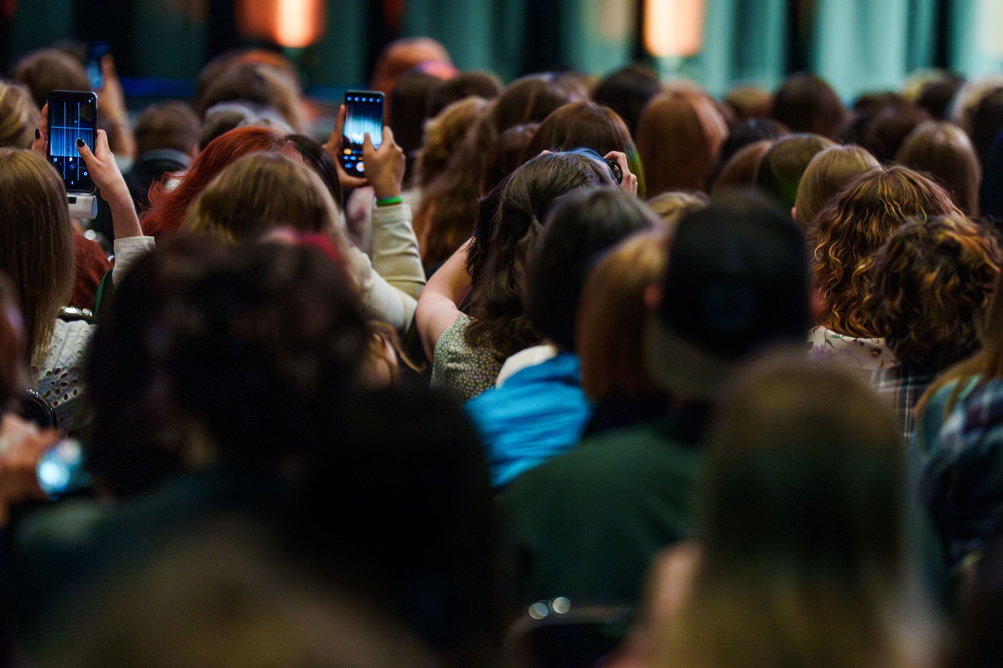 Vibrant crowd capturing live event using smartphones, creating silhouettes and engaging with the performance.