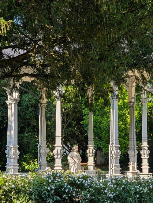 Free Ornate pavilion with classical statue surrounded by lush garden greenery. Stock Photo