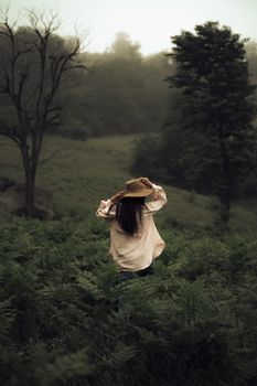Woman in a hat appreciating the natural scenery in a lush landscape.