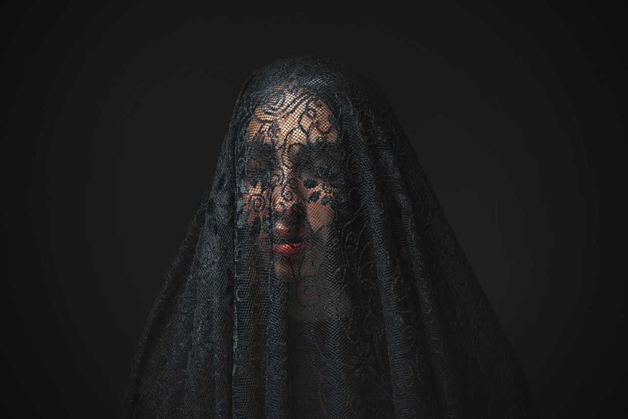 a portrait of a woman with a delicate lace veil creating an air of mys