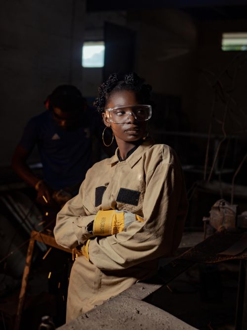 Free Young blacksmith working confidently in dimly lit workshop filled with sparks and tools. Stock Photo