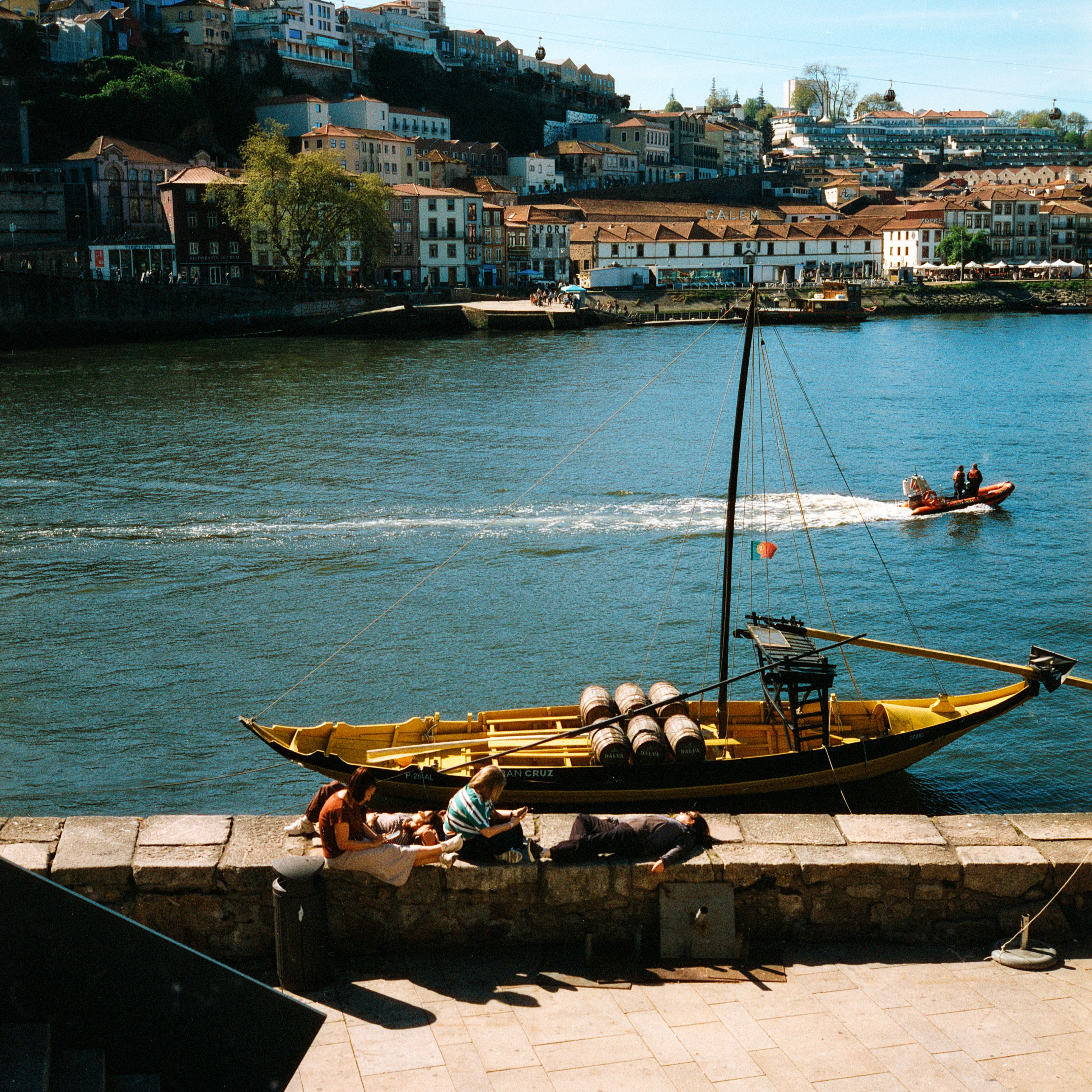 Relaxing by the Douro River in Porto with traditional boats and cityscape in view.