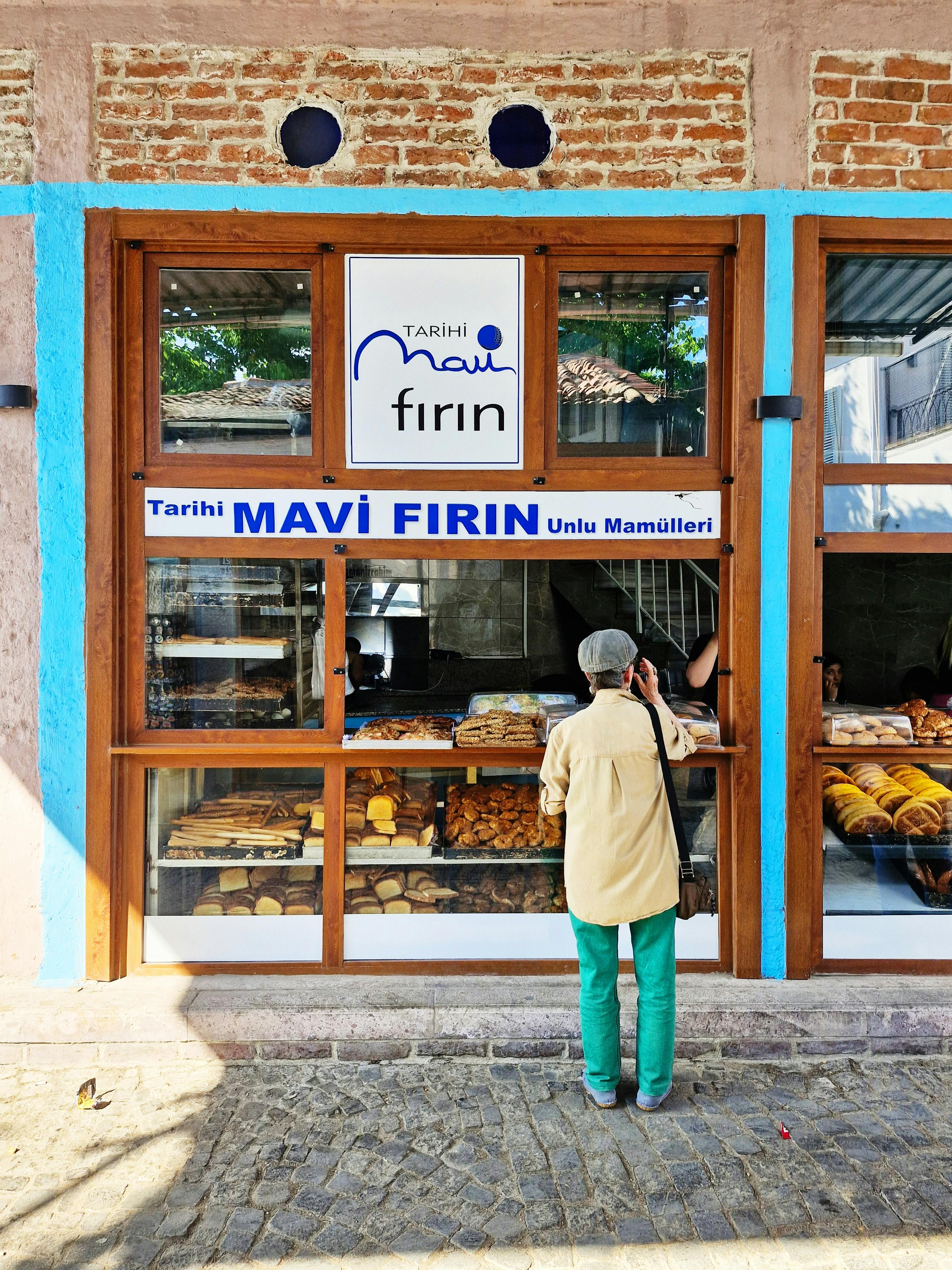 Person visiting a historic bakery in Ayvalık, Türkiye, showcasing traditional breads.