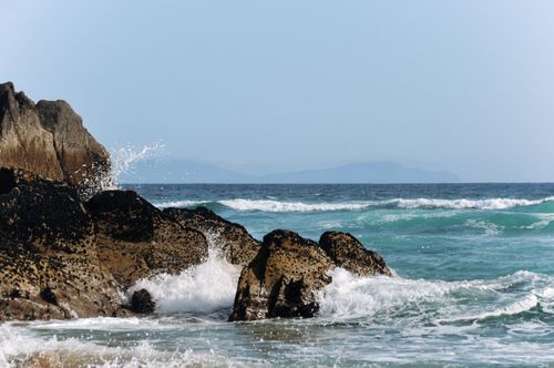 Free Waves crash against rugged rocks on a clear day at the Irish coastline, showcasing the power of the ocean. Stock Photo