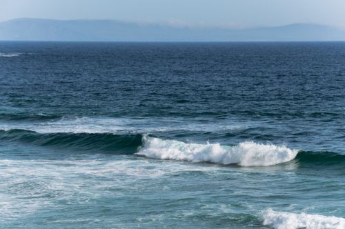 Free Gentle waves crashing on the shore of the Irish coast, showcasing nature's beauty and tranquility. Stock Photo
