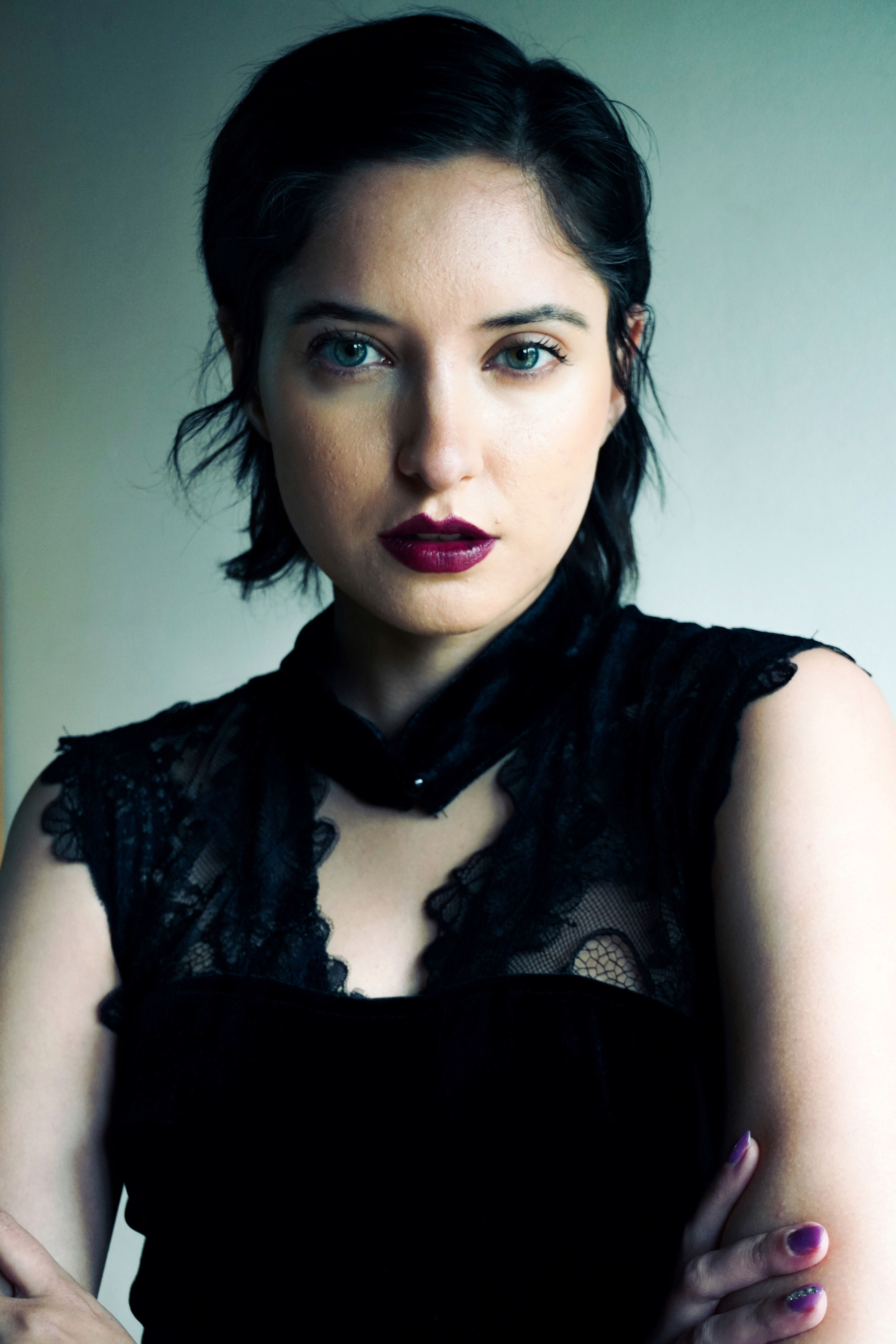 Striking portrait of a woman in a black lace dress with bold makeup and confident expression.