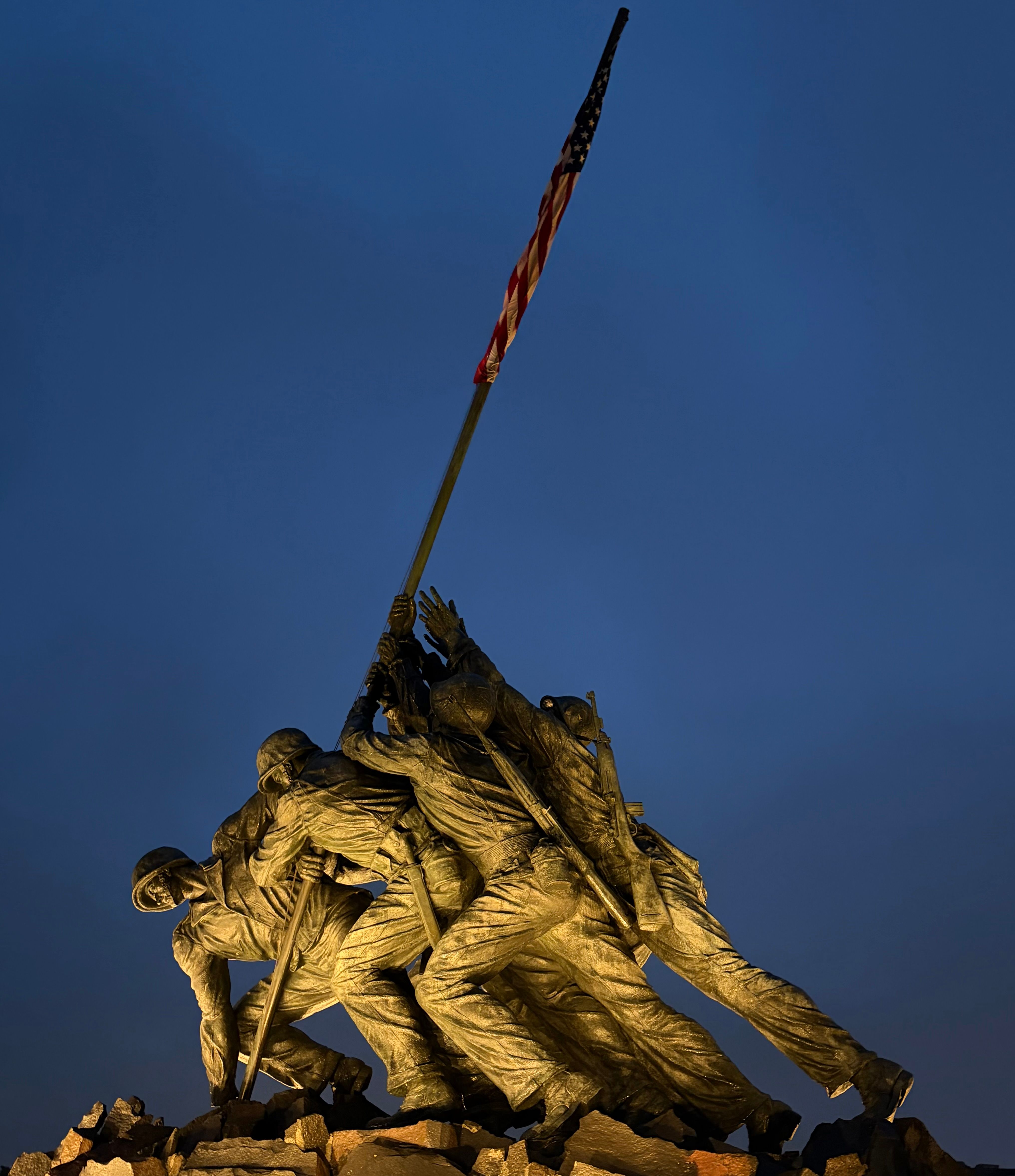 The Marine Corps War Memorial with American flag during twilight, symbolizing honor and bravery.