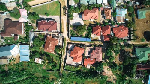 Free Explore a vibrant neighborhood with red-roofed houses amid lush greenery from above. Stock Photo