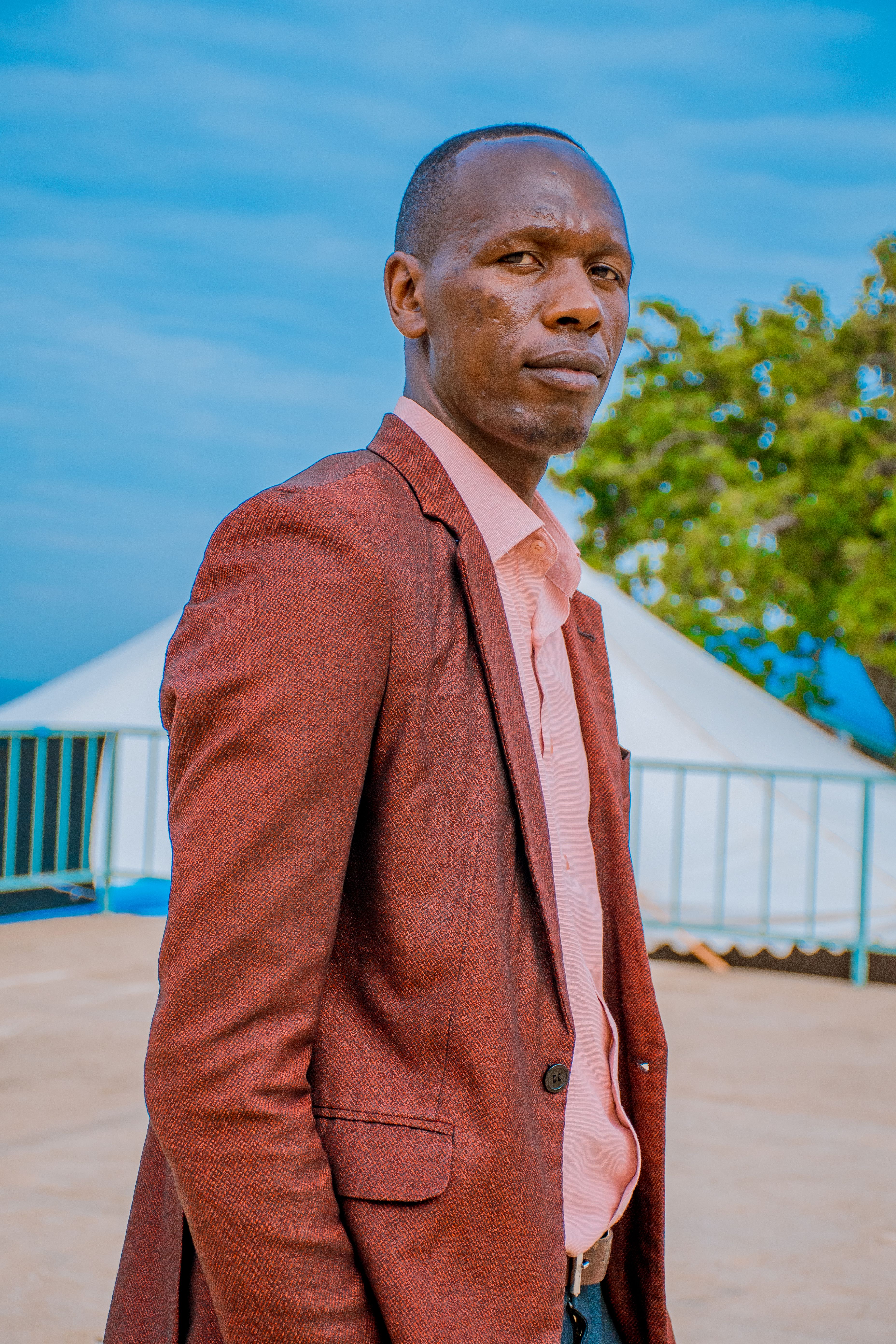 Portrait of a confident businessman outdoors against a blue sky, wearing a suit and tie.